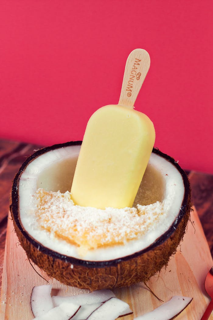 Refreshing coconut ice cream in a coconut shell with a vivid pink background, perfect for summer desserts.